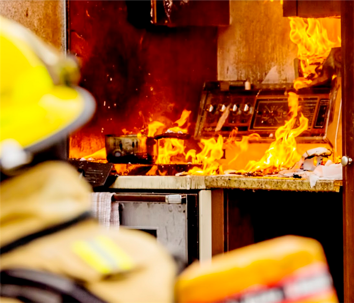 a kitchen on fire with firemen outside of the house